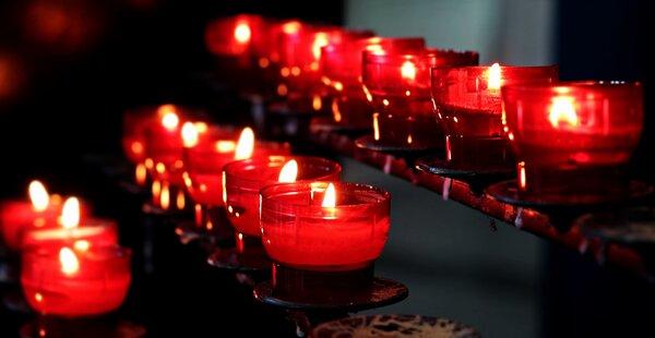 Kerzen Brennende rote Opferkerzen auf einem Kerzenständer